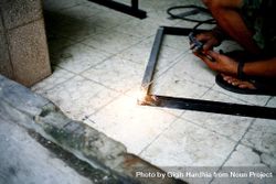 Person welding a metal frame on the ground 4jlPx0