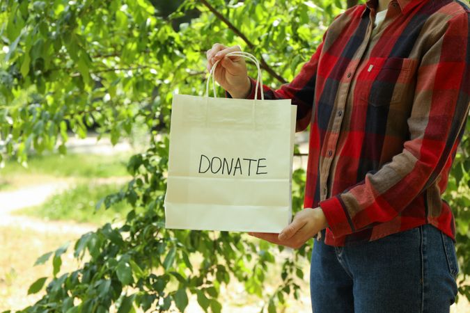 Woman holding paper bag with text Donate outdoor