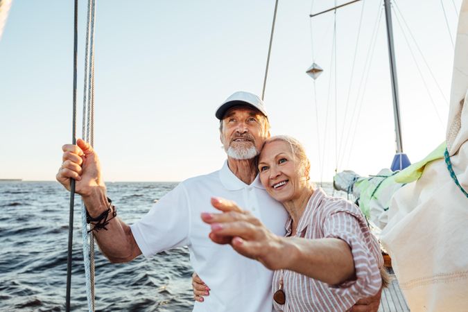 Content older couple sailing together with woman pointing at something in the distance