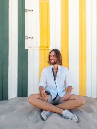 Cheerful guy using smartphone near striped wall