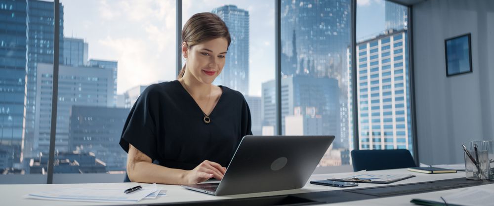 Portrait of Successful White Businesswoman Sitting at Desk Working on Laptop Computer in City Office.