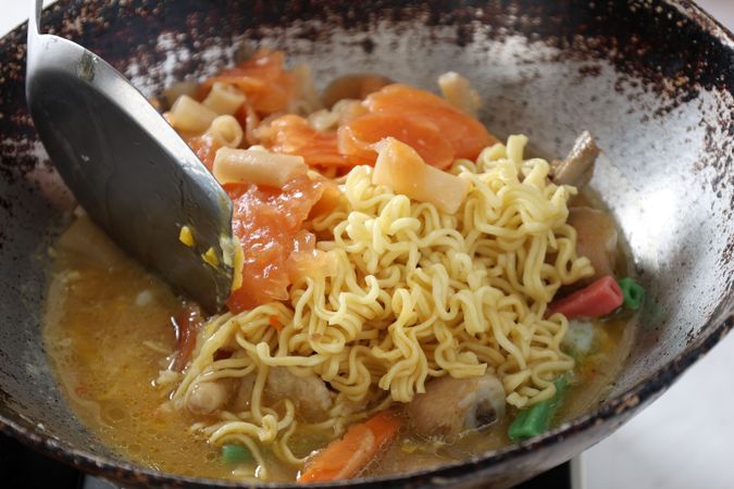 Close Up Cooking Seblak Bandung on Rustic Pan.