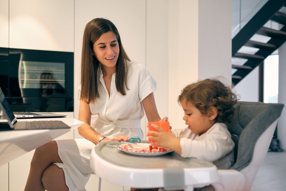Content working mother and eating toddler in kitchen