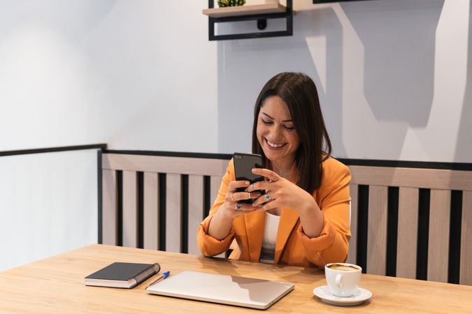 Woman using smartphone and working in cafe