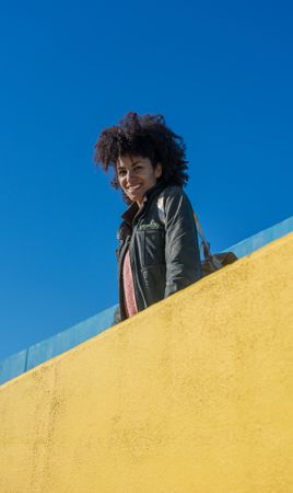 Black woman with afro hair leaning against brightly colored wall
