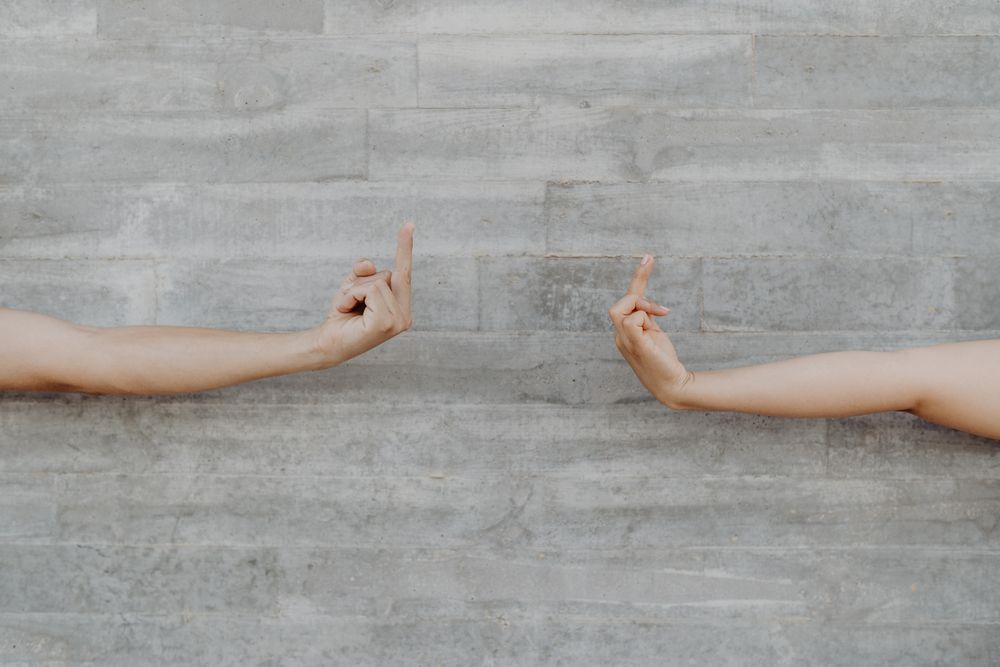 Hands raising finger up background of grey wall