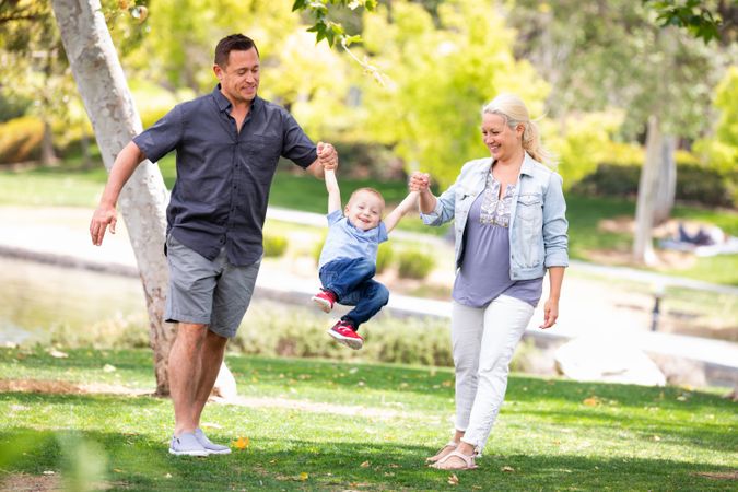 Young Mother and Father Swingging Their Son At The Park