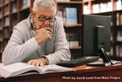 Mature man sitting in a classroom and reading a book 5pqrj4