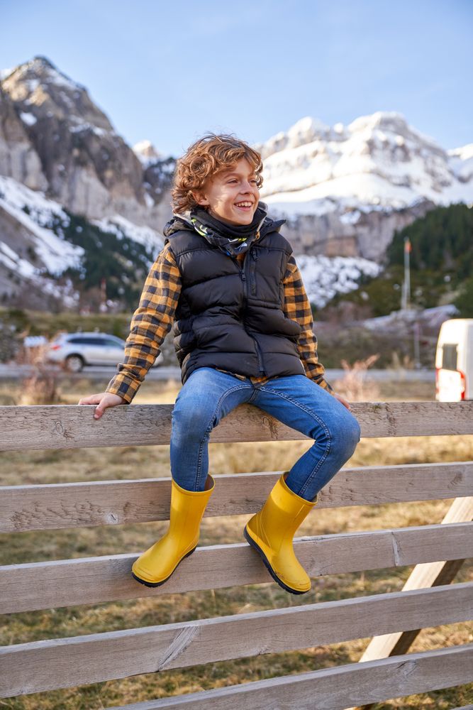 Happy boy sitting on wooden fence