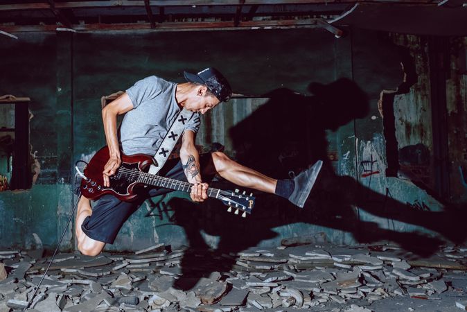 Musician playing electric guitar in abandoned place