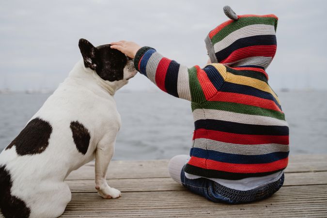 Anonymous kid petting dog on pier