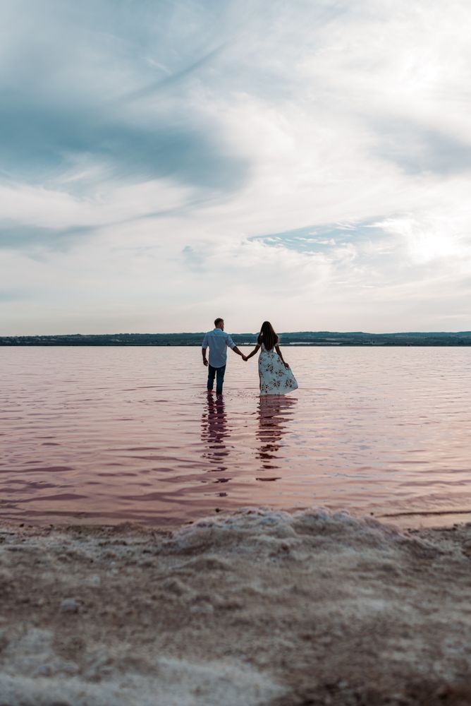 back view of adorable couple into an amazing beach with pink water