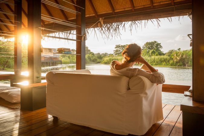 Woman sitting on couch and looking at calm lake