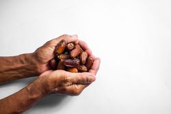 Hand hold date fruit on isolated blank background