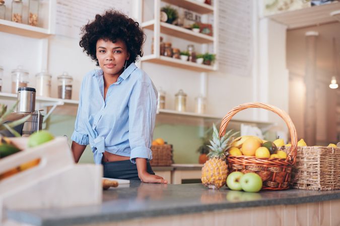 Portrait of confident young woman standing at counter in juice bar