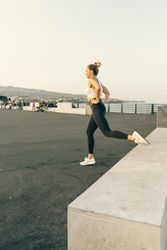 Athletic woman performing a lunge exercise in a public urban park by the sea