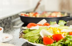 Closeup of fresh salad dish and female cooking in a pan