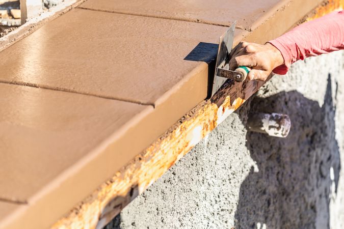 Construction Worker Using Stainless Steel Edger On Wet Cement Forming Coping Around New Pool