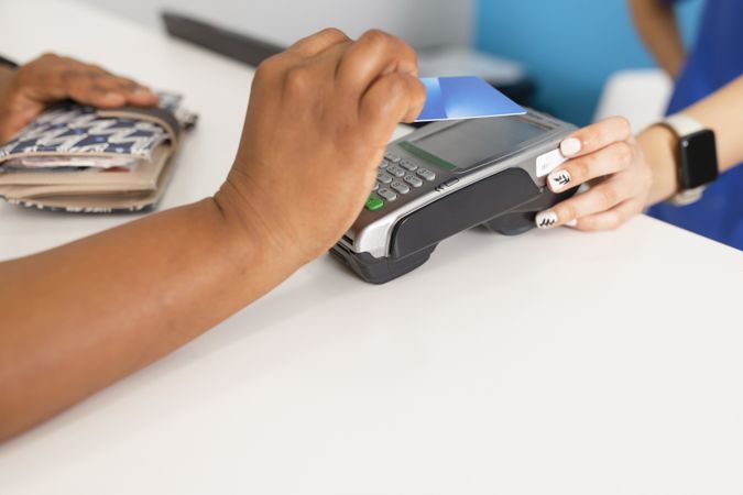 Black woman waving credit card over payment terminal