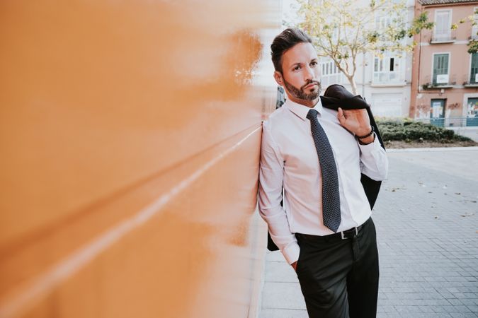 Adult smiling stylish man in costume near orange wall on street