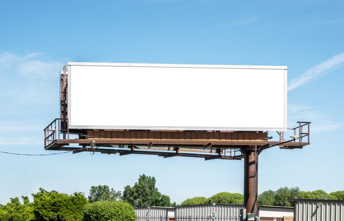 Digital billboard mockup next to road against a clear blue sky