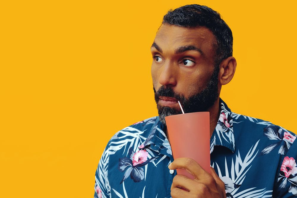 Male sipping a cocktail from orange cup with copy space