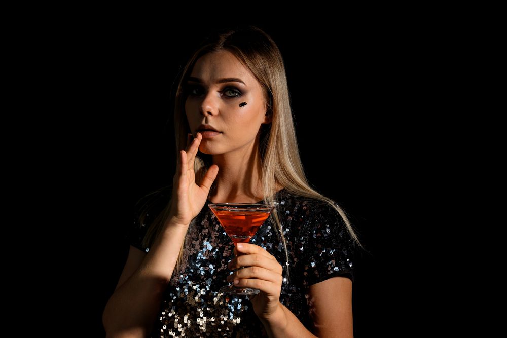 A woman at a party in the style of Halloween with a cocktail in her hands