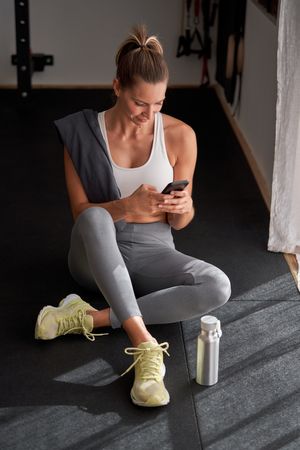 Positive woman using smartphone in gym
