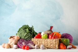 Wicker basket and vegetables on wooden background, copy space