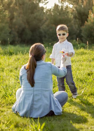 Son giving a bouquet of flowers to his mother in a field