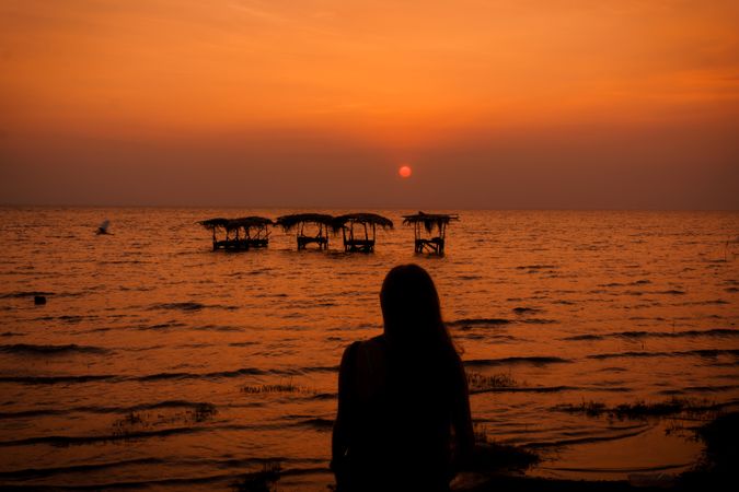 Woman near laundry in sea at sunset