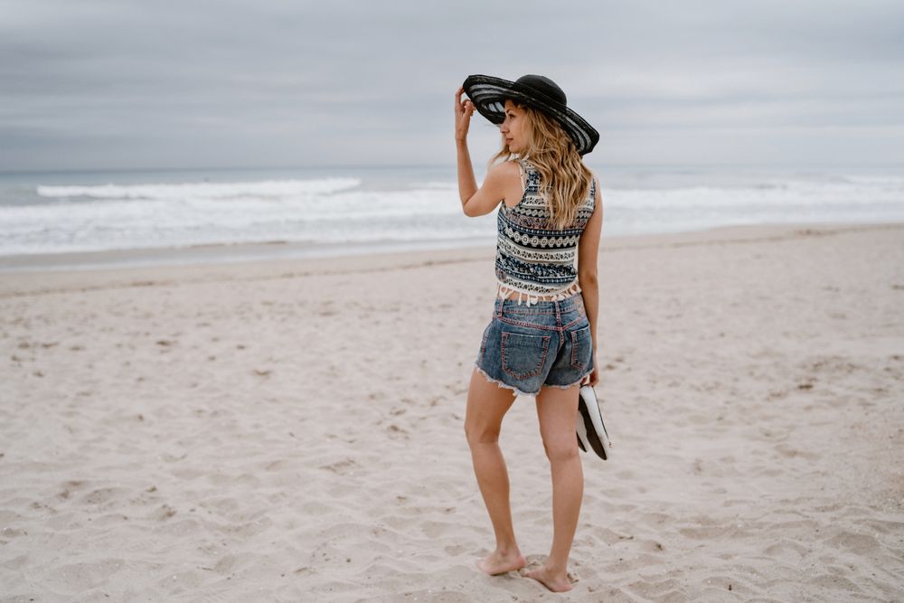 Young female walking barefoot on sandy beach