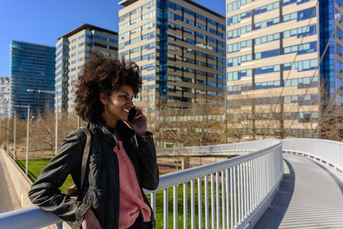 Woman with afro hair looking at her phone while walking.