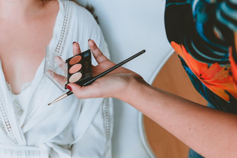 Woman hand with brush and powder near lady