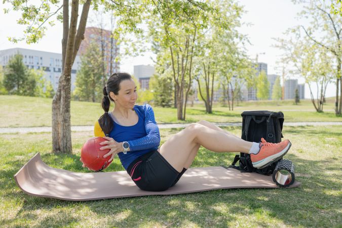 Athletic young woman in sportswear doing exercises with a ball