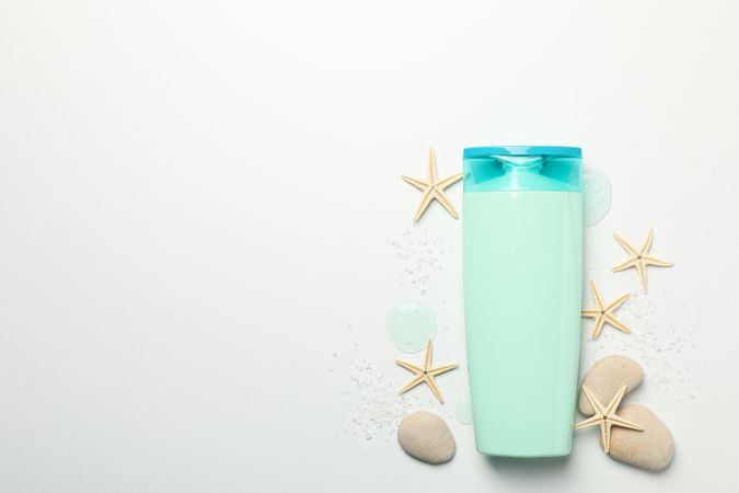 Blank cosmetic bottle and starfishes on light background