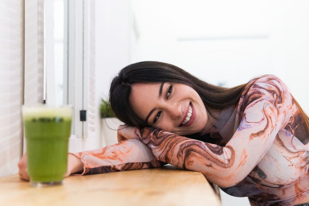 Content woman enjoying green beverage in bar