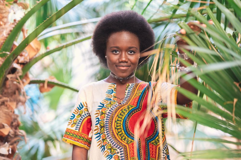 Cheerful Black woman amidst palm leaves