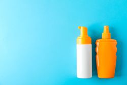Composition with sunscreen sprays on color background. Space for text, top view