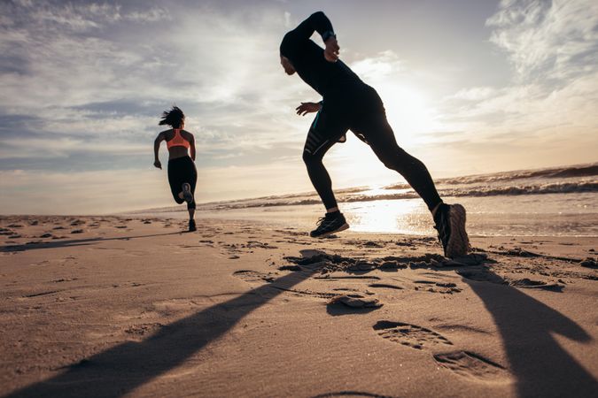 Rear view of two people sprinting on the beach