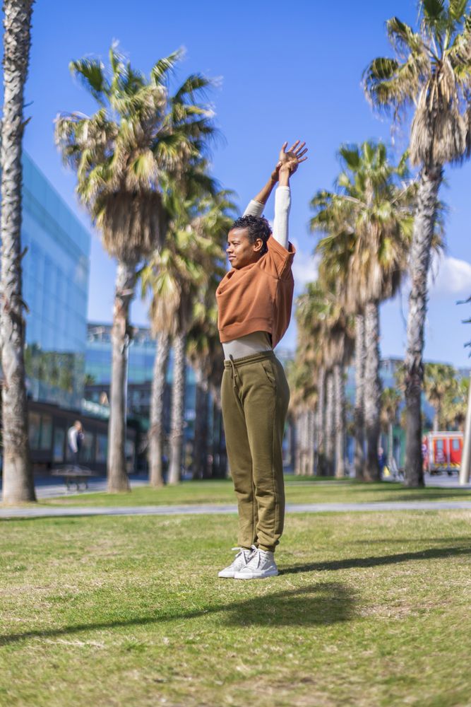 Black woman doing stretches under the palms in a promenade