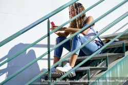 Serious female skater texting on phone on stairs, copy space 0gkzj0