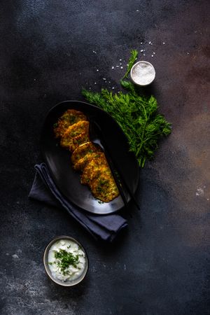 Top view of Ukrainian potato pancakes served with dill garnish and condiment