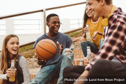 Boy holding a basketball sitting with friends on stairs having fun and laughing 4jjJ84