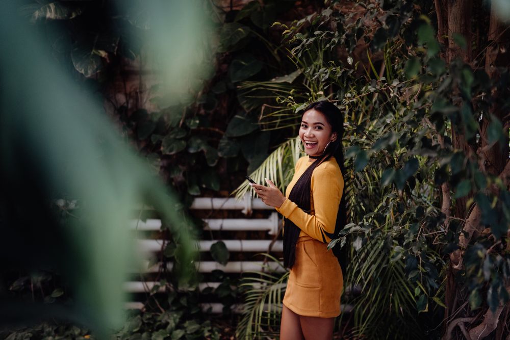 Charming long haired Asian woman browsing smartphone in botanical garden