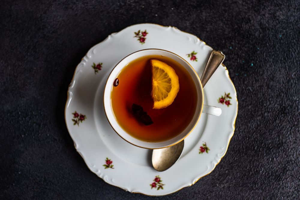 Top view of tea served in cup and saucer with lemon slice
