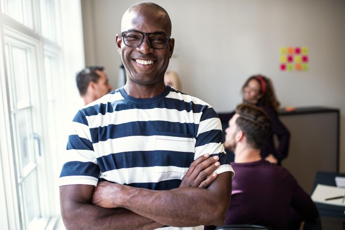 Smiling Black man in office with arms folded