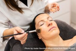 Professional cosmetologist brushing product on client's forehead 5XrYlM