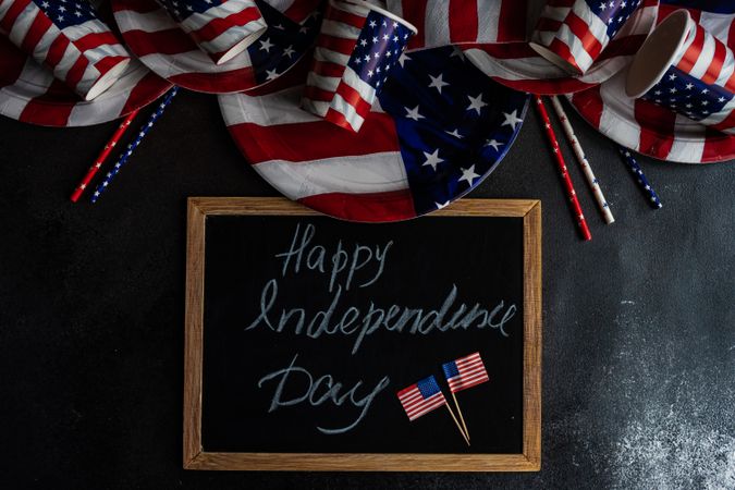 Chalkboard surrounded by American flag plates and cups with the words "Happy 4th of July"