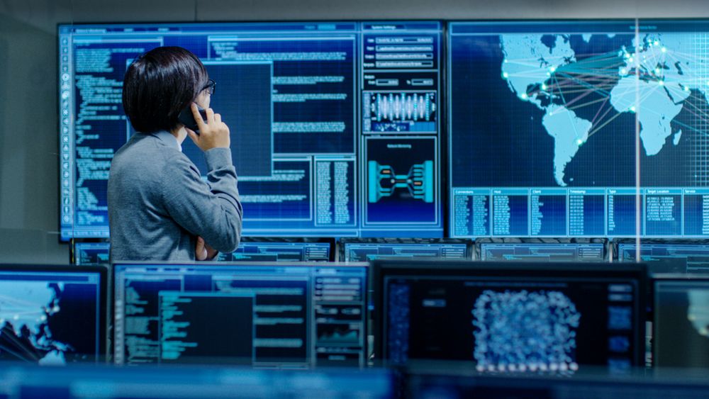 In the System Control Room IT Administrator Talks on the Phone.